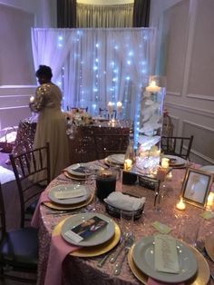 a table set up for a formal function with plates and candles on it, in front of a curtained window