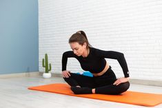 a woman in black shirt doing yoga on orange mat