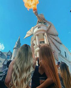 three girls standing in front of a building with a dragon on it's head