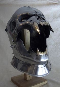 a metal helmet with large teeth on top of a wooden stand