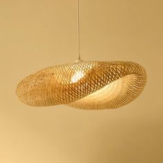 a woven light fixture hanging from a ceiling in a room with beige walls and flooring