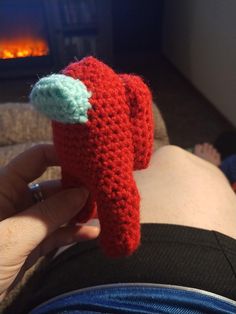 someone is holding a crocheted red object in their left hand and it looks like an elephant