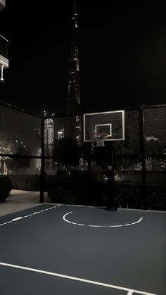 an empty basketball court in the middle of a city at night