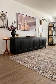 a living room filled with furniture and pictures on the wall next to a large rug