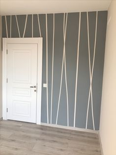 an empty room with a white door and grey striped wallpaper on the opposite wall