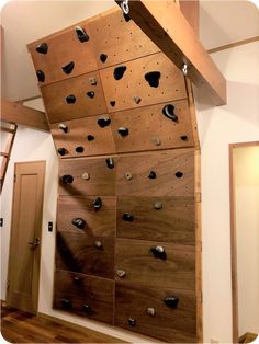 the climbing wall is made from wood and has black rocks on it