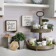 three tiered trays with coffee cups and succulents on them in the corner of a kitchen