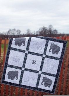 an elephant themed quilt hanging on a fence