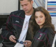 the man and woman are looking at their cell phones together in front of a truck