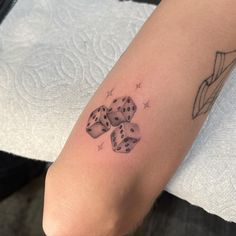 a person with a tattoo on their arm holding two dices