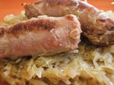 two sausages and sauerkraut on an orange plate with grated cabbage