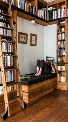 a woman laying on top of a bed next to a book shelf filled with books