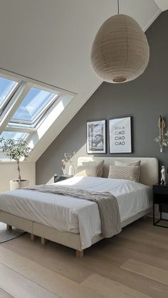 a large bed sitting under a skylight in a bedroom next to a wooden floor