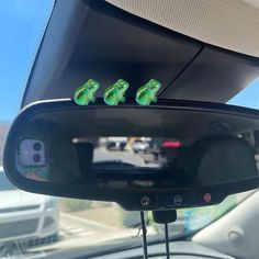 two green frogs sitting on top of a mirror in the back seat of a car