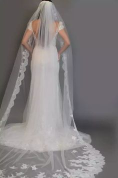 the back of a bride's wedding dress with a veil on her head and shoulders