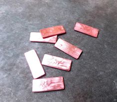 four pieces of red wood sitting on top of a floor next to a knife and fork