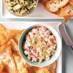 a plate with crackers, dip and salad on it next to a bowl of chips