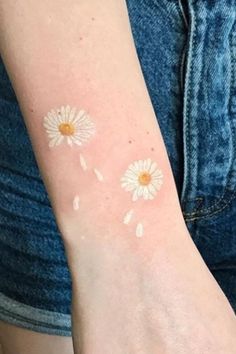 a woman's arm with white and yellow flowers on the back of her arm