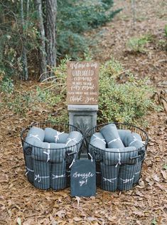 three black baskets with chalk writing on them are sitting in the leaves near a sign that says imagine you