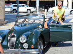 an older man sitting in the driver's seat of a green car