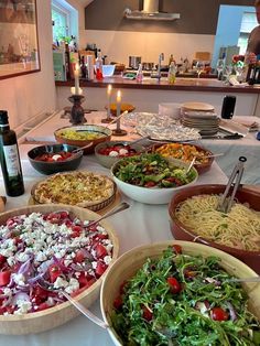 a table topped with lots of bowls filled with food next to a bottle of wine