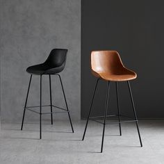 two black and brown stools sitting next to each other in front of a gray wall