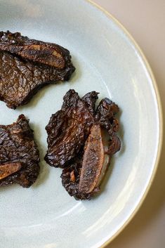 three pieces of beef on a white plate