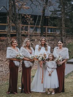 a group of women standing next to each other in front of some trees and grass