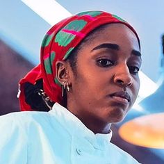 a woman wearing a red bandana standing in front of a plate