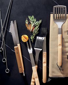 various kitchen utensils are laid out on a black counter top, including knives and spatulas