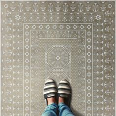 someone is standing on the floor with their feet up in front of a patterned wall