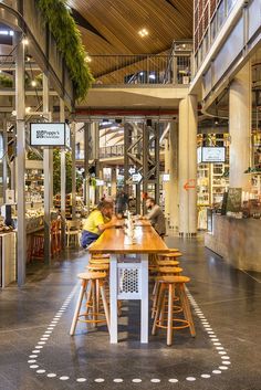 people sitting at wooden tables in a large building