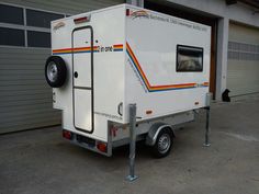 a small white trailer parked in front of a garage