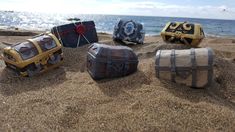 four pieces of luggage sitting in the sand at the beach