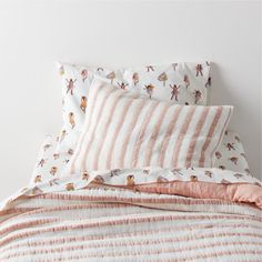 a bed with pink and white striped comforter next to two pillows on top of it