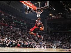 a basketball player dunking the ball in front of an arena full of people watching