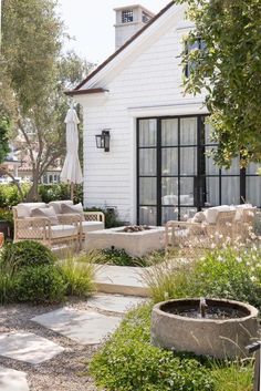 an outdoor patio with chairs and tables next to a white brick building in the background