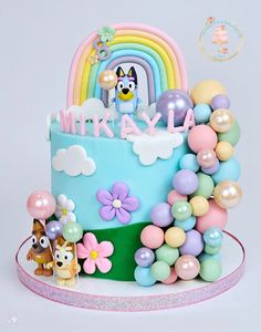 a birthday cake decorated with balloons, flowers and a dog on the top is for a child's first birthday