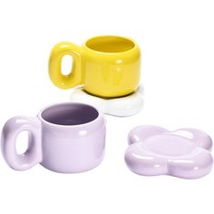 three different colored cups and saucers on a white surface, one with a yellow cup in the middle