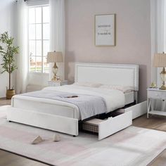 a white bed with two drawers underneath it in a living room next to a window