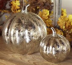 two silver pumpkins sitting on top of a wooden table