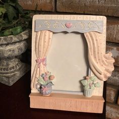 a small mirror sitting on top of a wooden shelf next to a potted plant