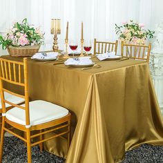 the table is set with gold cloths and place settings for two people to sit at