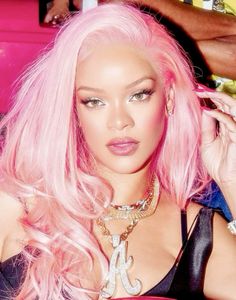 a woman with pink hair wearing a black top and gold chains on her neck is posing for the camera