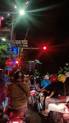 a group of people riding scooters down a street at night