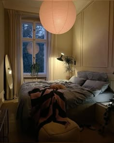 a bed room with a neatly made bed next to a large window and a lamp