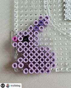 there are many purple and black beads in the plastic case on the table next to each other