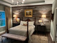 a bedroom with wood paneled walls and a bed in the middle, along with two lamps on either side of the bed