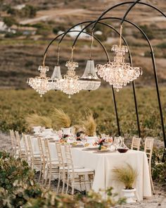 an outdoor dining table with chandeliers hanging from it