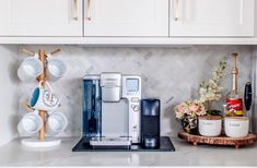 a coffee maker sitting on top of a kitchen counter next to cups and saucers